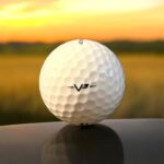 Återvunnen golfboll i vit färg av modellen Taylormade V3 fotad bakifrån