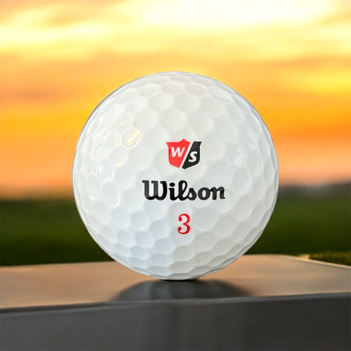 Återvunnen golfboll i vit färg av modellen Wilson duosoft fotad framifrån med röd logotyp