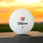 Återvunnen golfboll i vit färg av modellen Wilson duosoft fotad framifrån med röd logotyp